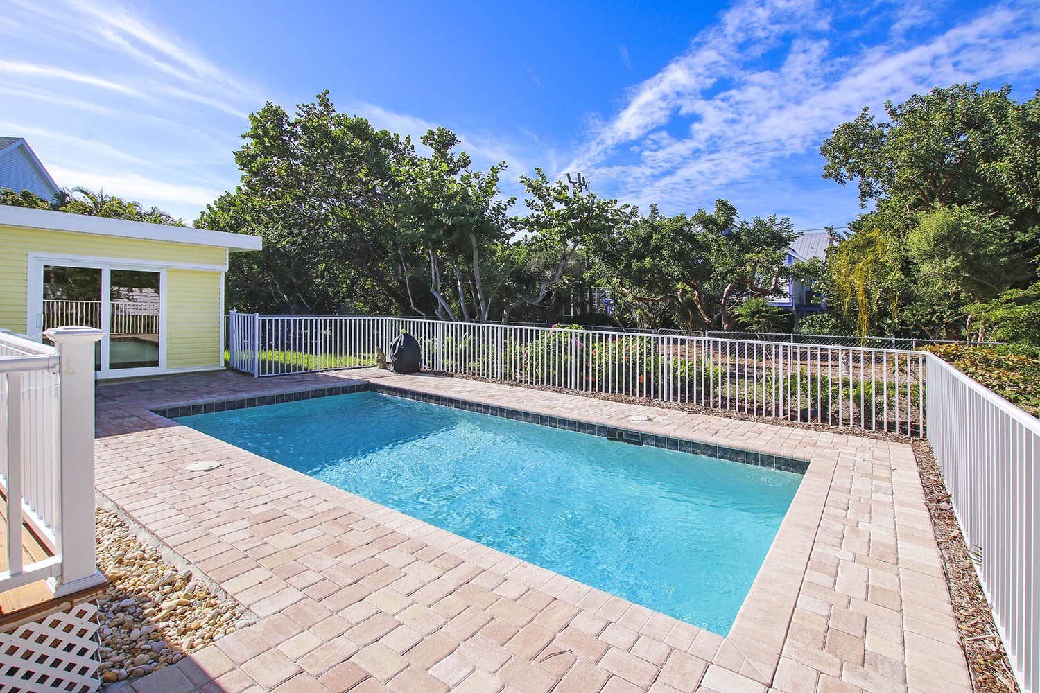 A pool with brick pavers and a fence.