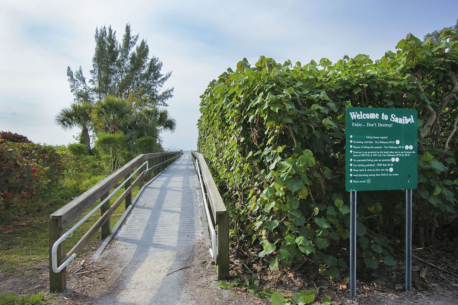 A sign on the side of a road near some bushes.