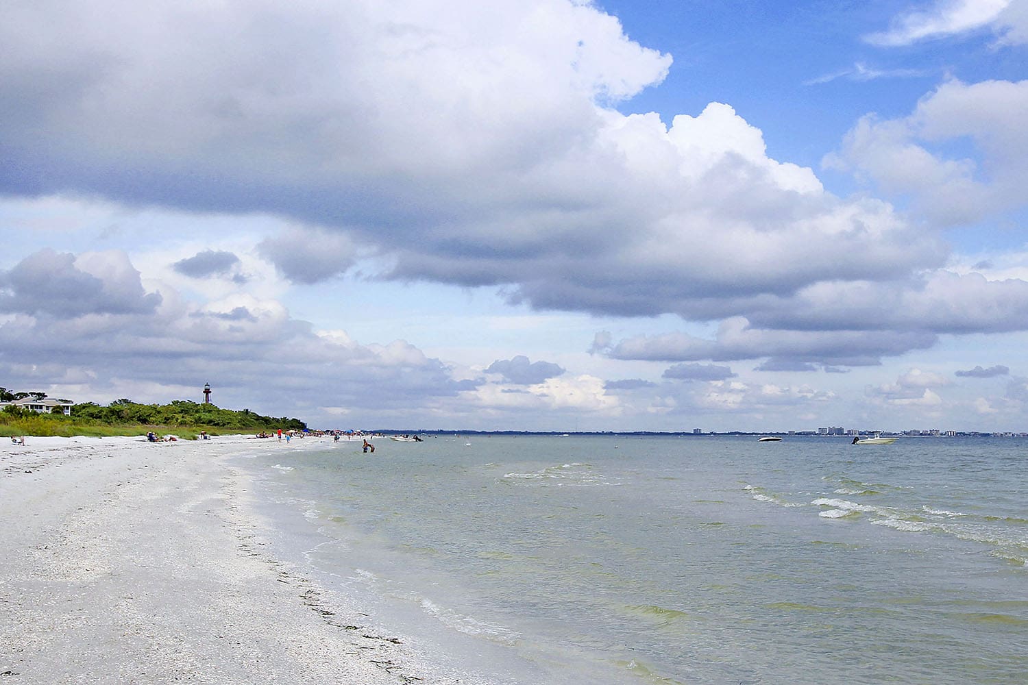 A beach with people on it and clouds in the sky.