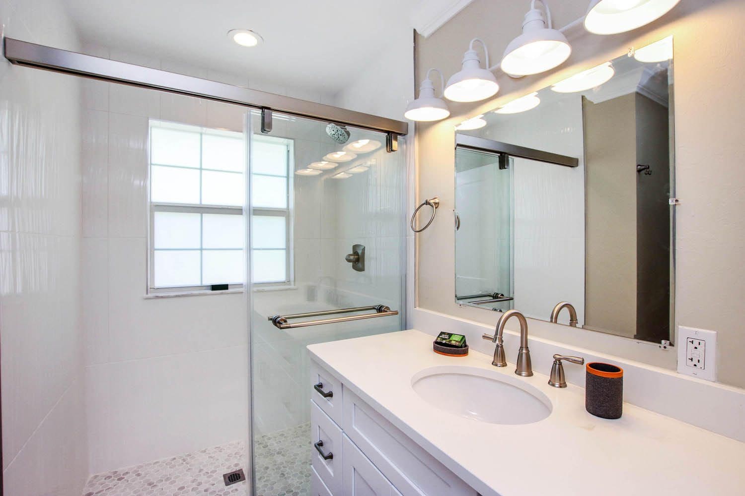 A bathroom with a sink, mirror and shower.