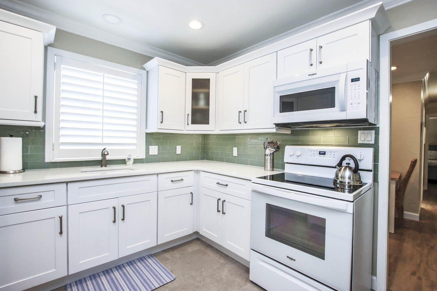 A kitchen with white cabinets and appliances in it