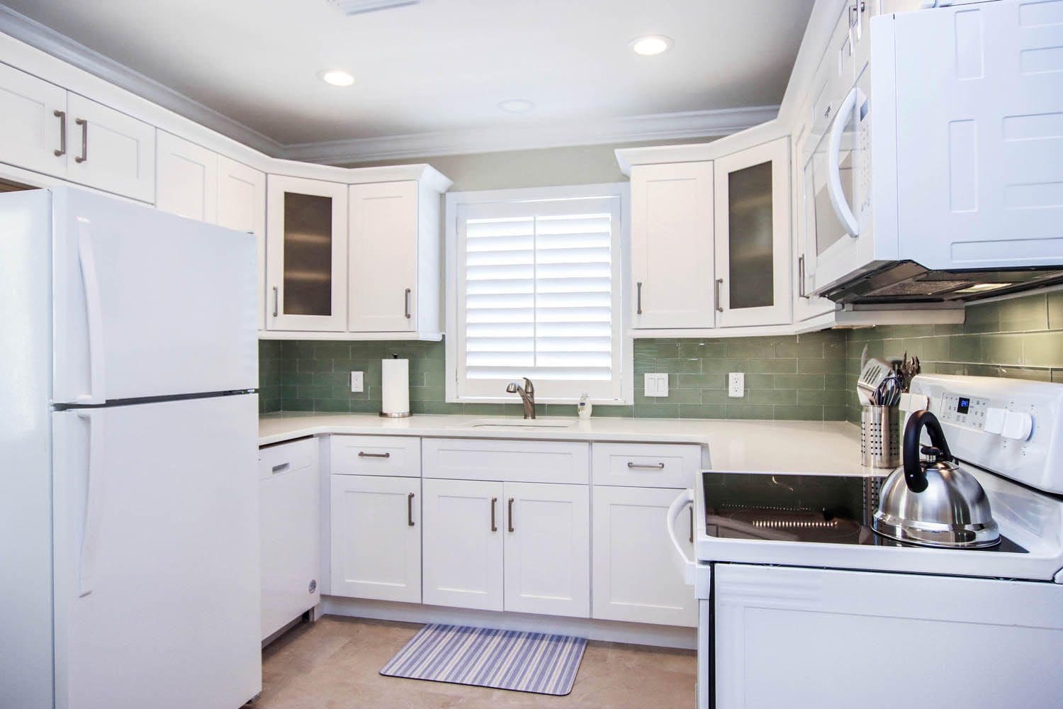 A kitchen with white cabinets and appliances in it