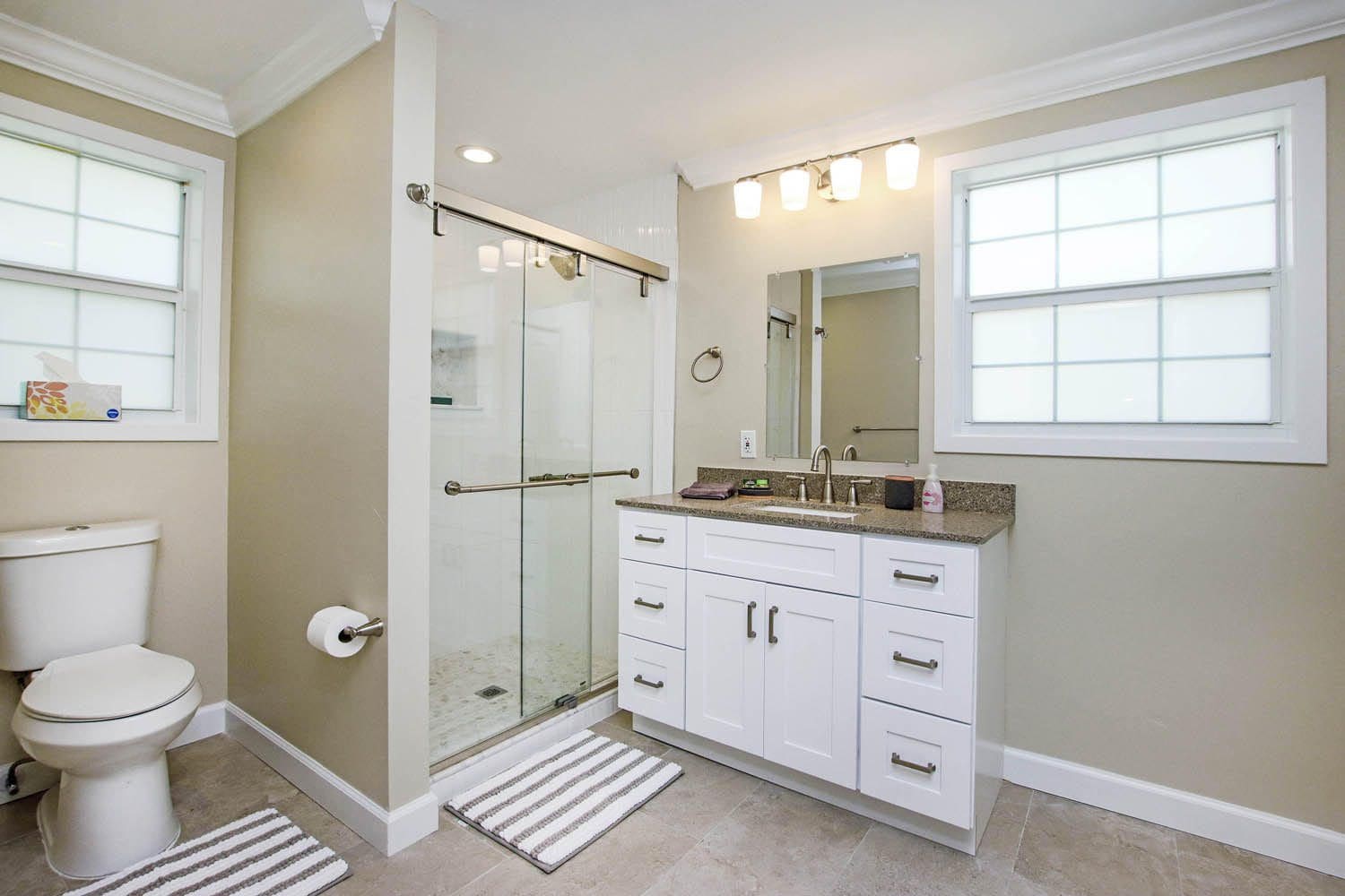 A bathroom with a shower, sink and mirror.