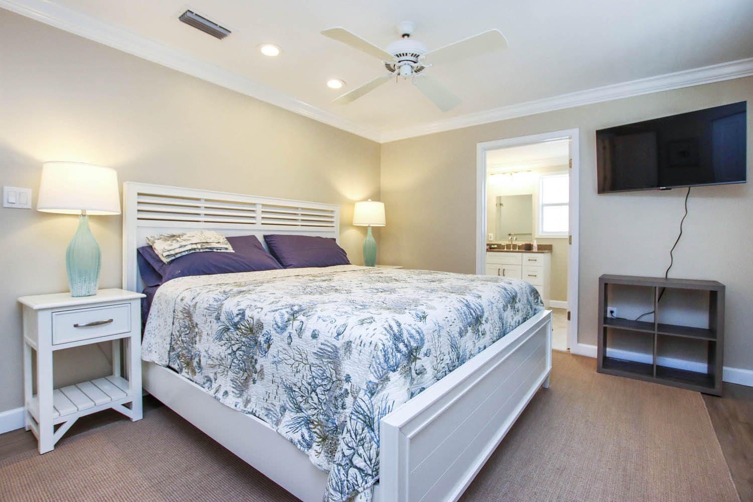 A bedroom with a bed, dresser and tv.